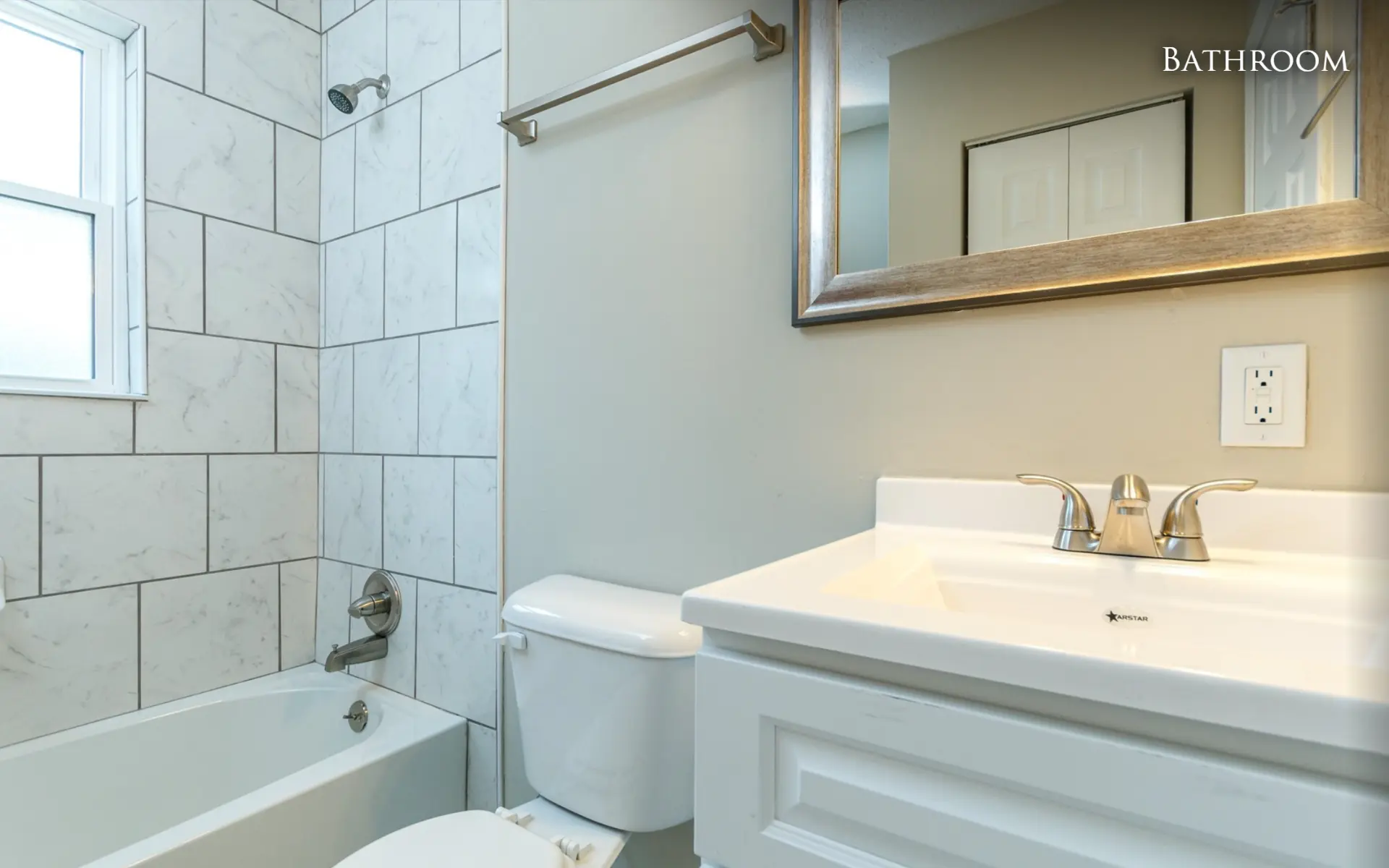 Unit B bathroom with vanity and tiled tub surround