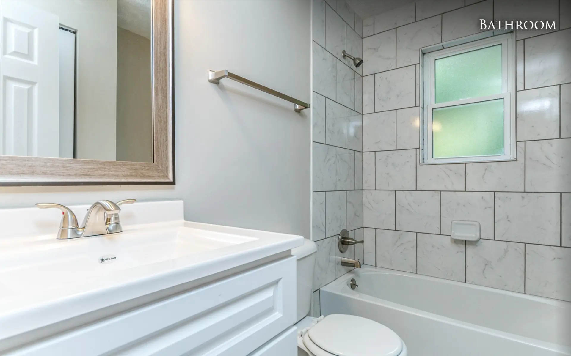 Unit A bathroom with vanity and tiled tub surround